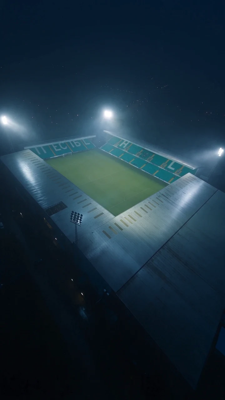 A football stadium illuminated by floodlights on a misty night
